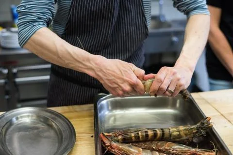 Human hands breaking up shell of Norway lobster in kitchen during cookery cla Stock Photos