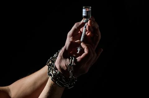 Human hands chained in chains are taking an injection into a syringe from an amp Stock Photos