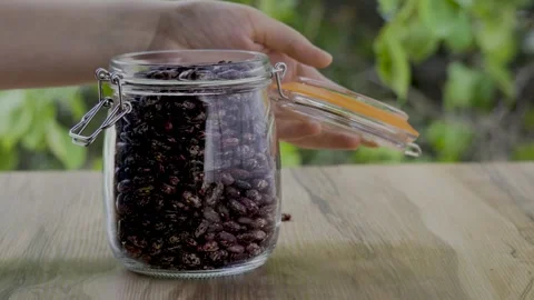 Human hands closing glass jar with pinto beans on wooden table 4k Stock Footage 341341191