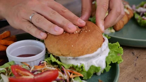 Human hands cover burger with melted cheese with top bun. Delicious hot dish on Stock Footage 239703483