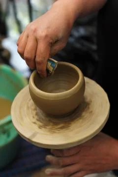 Human hands creating clay pot on wheel Stock Photos