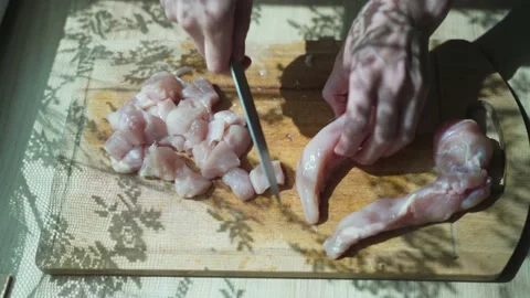 Human hands cutting on cubic, raw tender chicken breast or fillet with sharp Stock-Footage 133814674