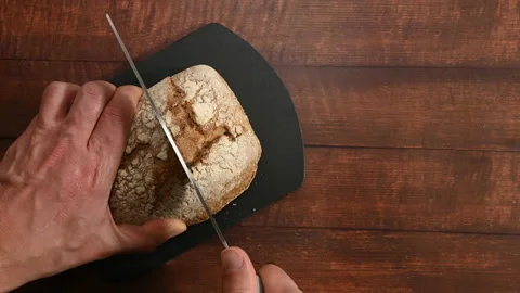 Human hands cutting a homemade bread on a slate cutting board.  Stock Footage 196594731