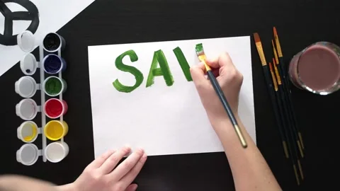 Human hands draw poster with paints and brush on blank sheet with call to save Stock Footage 172008340