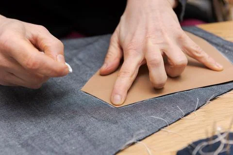 Human hands drawing a master template with tailor's chalk on fabric for makin Stock Photos