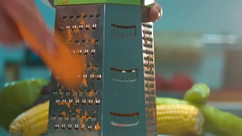 Human hands grate raw carrot on a metal grater Stock Footage 134469053