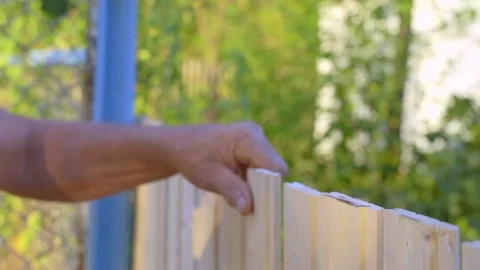 Human hands with a hammer make sweeping movements, fixing the wooden fence Stock Footage 137384119