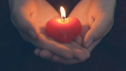 Human hands hold heart shaped burning candle against dark background. Young w Stock Footage 112718350
