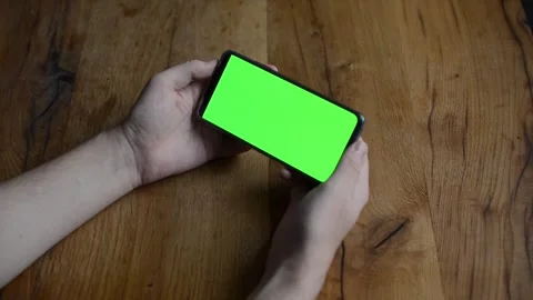 Human hands hold an Smartphone in Vertical Mode with green chroma key close-up Stock Footage 245610716