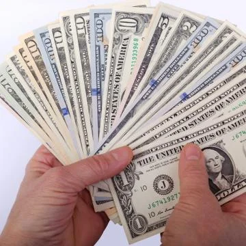 Human hands, holds a fan, with stack of different US dollars banknote. On whi Stock Photos