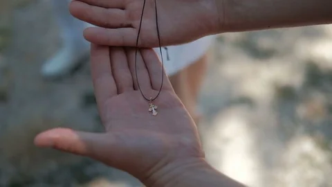 In human hands lies an Orthodox little golden cross on a string. Video stock 82171663
