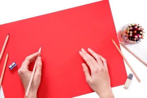 Human hands with pencil drawing something on the red paper isolated on white Stock Photos