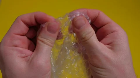 Human hands popping the bubbles in bubble wrap. Selective focus, close up. Stock Footage 168899036