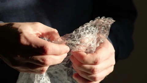 Human hands popping the bubbles in bubble wrap. Selective focus, close up. Stock Footage 168899782