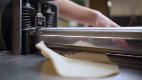 Human hands in process of making fresh pasta dough with machine rolling out Stock Footage 189265480