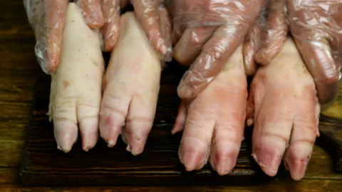 Human hands in rubber gloves funny banging with pork hooves. Stock Footage 129509146