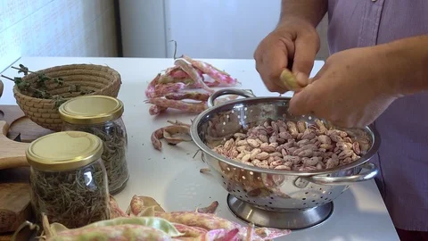 Human hands shelling fresh raw red kidney bean pods on table in the kitchen Stock Footage 112892018
