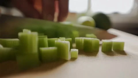Human hands slicing celery over a wooden table for a vegan meal Stock Footage 300014777