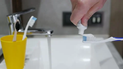 Human hands Squeeze out toothpaste on a toothbrush over a sink. Dental care Stock Footage 212618612