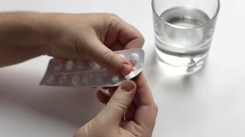 Human hands take out a pill from the package and take a glass of clean water Stock Footage 146898264