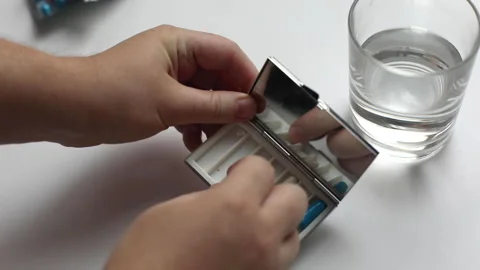 Human hands take out a pill from a pill box, take a glass of pure water Stock Footage 146959603
