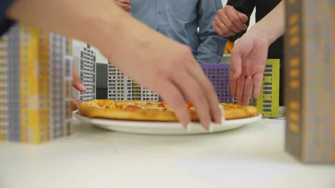 Human hands take slices of pizza from the table with model of houses Stock Footage 121287452