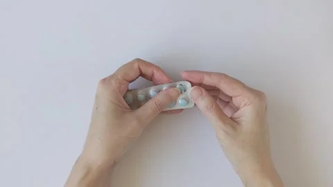 Human hands taking out pill from blister pack. Package containing blue tablets Stock Footage 330552343