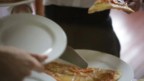Human hands taking pieces slices of hot tasty italian pizza from table to plate Stock Footage 219610514