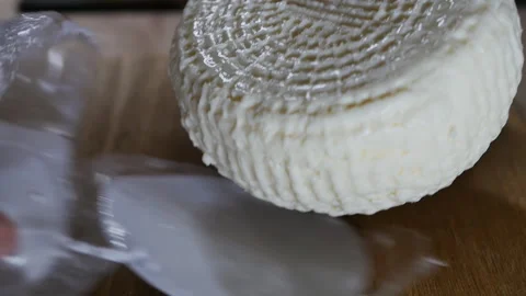 Human hands unpacked hard round cheese from vacuum packaging Stock Footage 168983095
