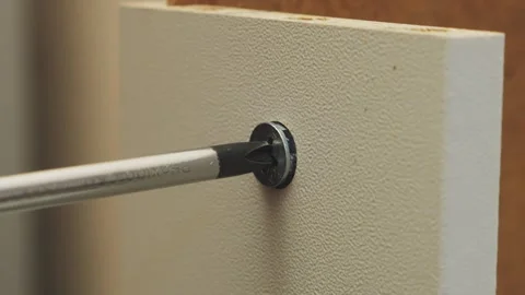 Human hands use a screwdriver to screw bolts into furniture with drawers. T.. Stock Footage 340475480