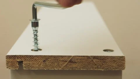 Human hands use a screwdriver to screw screws into furniture with drawers. .. Stock Footage 342056578