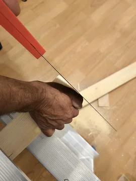 Human hands using a hand saw to cut a wooden block 스톡 사진