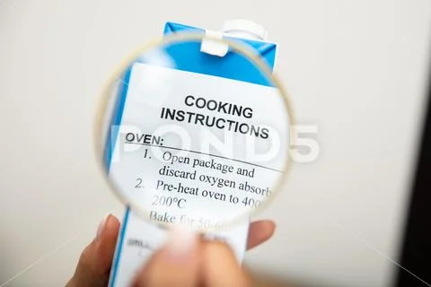 Human Holding Magnifying Glass Over Cooking Instructions Stock Photos