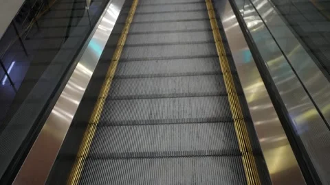 Human legs using a moving down escalator in the mall. Pair in the shoes sneakers Stock Footage 285063692