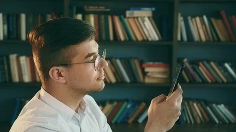 Human in library with cellphone. Modern technologies. People use mobile phone. Stock Footage 114460441