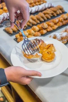 Human picking assorted pastry into white plate at buffet party Foto stock