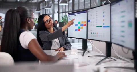 Human Resource Manager Coaches Two Women Using HR Software On Desktop Compute Stockfoto's