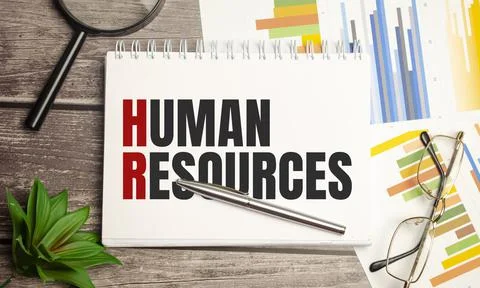 Human resources word concept on notepad and magnifier on wooden background Stock Photos