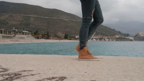 Human in ripped jeans and orange sneakers is on the sand coast. Stock Footage 73067341