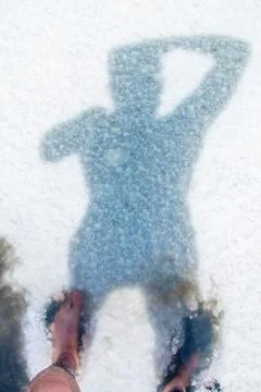 Human shadow on the salt surface of the lake, abstract pattern on a white bac Stock Photos