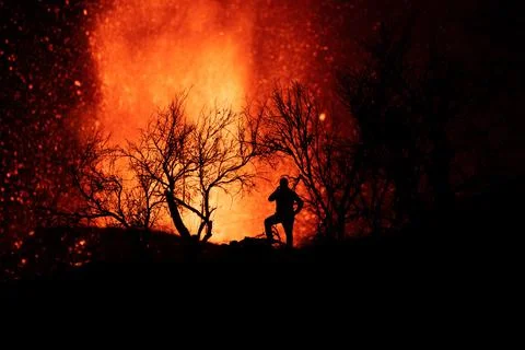 Human silhouette standing against exploding lava in La Palma Canary Islands 2 库存照片