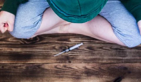 Human sitting in front of syringe Stock Photos