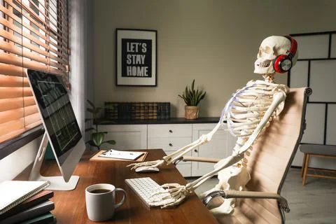 Human skeleton with headphones using computer at workplace Stock Photos