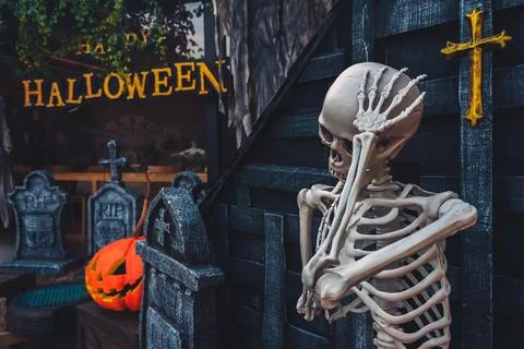 Human skeleton prop posing with hand on head near gravestones and Happy Hal.. Stock Photos