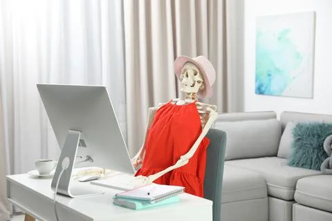 Human skeleton in red dress using computer indoors Stock Photos