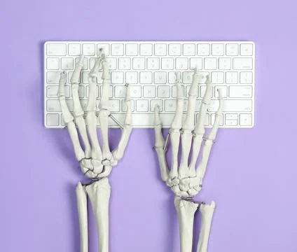 Human skeleton using computer keyboard on violet background, top view Stock Photos