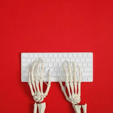 Human skeleton using computer keyboard on red background, top view. Space for Stock Photos