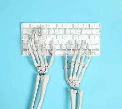 Human skeleton using computer keyboard on light blue background, top view Stock Photos