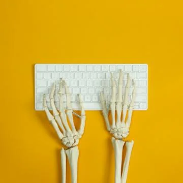 Human skeleton using computer keyboard on yellow background, top view Stock Photos