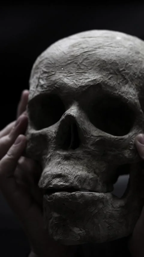 Human skull made of plaster and paper in hands on black background Video stock 347026061
